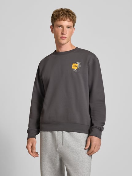 Männermodel trägt Relaxed Fit Sweatshirt aus Baumwoll-Mix mit Label-Detail von The North Face in Dunkelgrau, elastische Abschlüsse, Nahaufnahme Oberkörper.