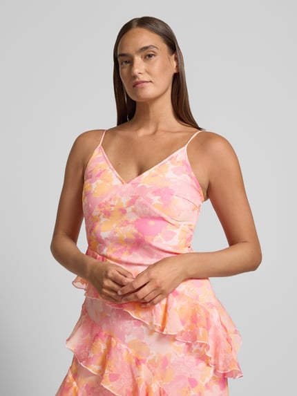 Frauenmodel trägt Figurbetontes Midikleid mit Rüschen Modell 'SMILLA' von Vero Moda, Chiffon mit rosa-gelbem Allover-Muster, Nahaufnahme Oberkörper.