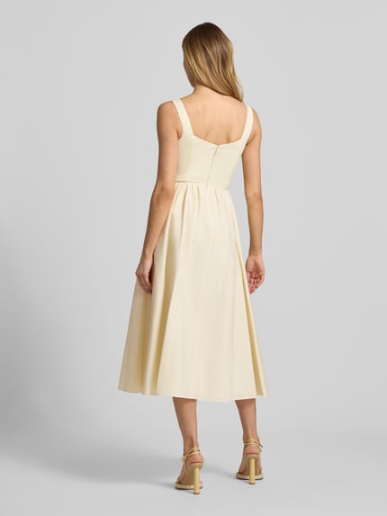 Frauenmodel trägt Cocktailkleid mit rückseitigem Reißverschluss von Jake*s Cocktail aus Baumwoll-Mix mit Stretch-Anteil, A-Linie, Midikleid in Creme mit glatter Textur, Rückseitiger Reißverschluss, Rückenlänge 123 cm, Brustweite 40 cm, Ganzkörperansicht Rückansicht.