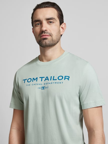 Męski model ma na sobie Regular Fit T-Shirt aus reiner Baumwolle od Tom Tailor, jednolity kolor, nadruk z logo, okrągły dekolt, bawełna, zbliżenie na górną część ciała.
