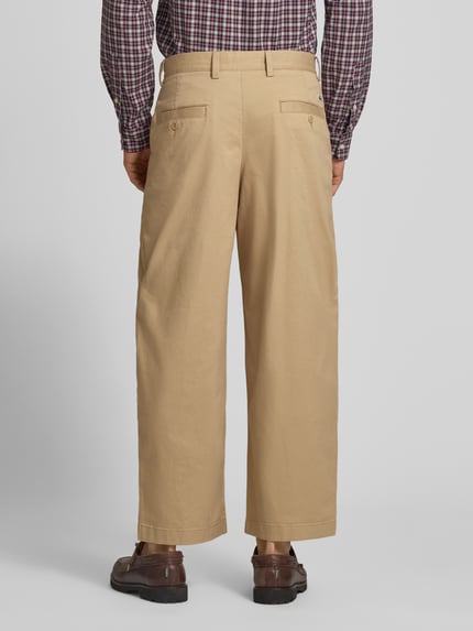Männermodel trägt Loose Fit Weite Hose aus Baumwoll-Mix von Lacoste in Beige, glatte Textur, Herren Weite Hose, Ganzkörperansicht Rückansicht.