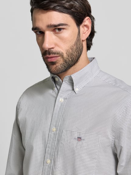Männermodel trägt Slim Fit Freizeithemd mit Logo-Stitching von Gant in Grau-Weiß mit Button-Down-Kragen, reine Baumwolle, Nahaufnahme Oberkörper.