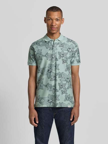 Männermodel trägt Slim Fit Poloshirt mit floralem Allover-Print von Lerros aus Reine Baumwolle, mintgrün mit schwarzen Blütenmotiven, Polokragen, kurzärmelig, Rückenlänge bei Größe M 72 cm, Ganzkörperansicht von vorne.