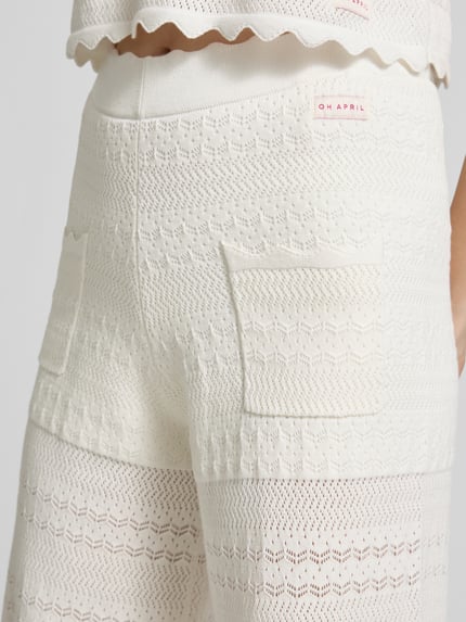 Vrouwenmodel draagt Strickhose met Eingrifftaschen model 'Aurea' van OH APRIL in crème, katoen- en viscosemix, labelpatch, detailopname rug.