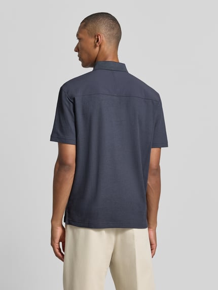 Männermodel trägt Regular Fit Poloshirt aus reiner Baumwolle Modell 'Pe_RibNylon' von BOSS Orange in Dunkelblau, Ganzkörperansicht Rückansicht.
