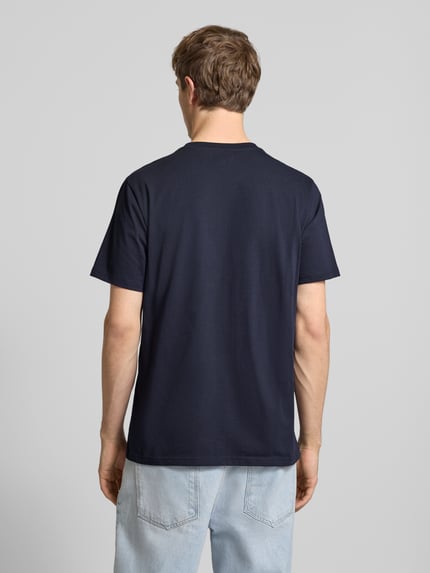 Männermodel trägt Regular Fit T-Shirt mit Logo-Patch von Carhartt Work In Progress in Dunkelblau, Baumwolle, Ganzkörperansicht Rückansicht