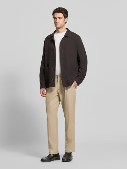 Männermodel trägt Regular Fit Bundfaltenhose mit Bügelfalten Modell 'Lui' von Strellson in Beige, unifarben, Webware, Ganzkörperansicht von vorne.
