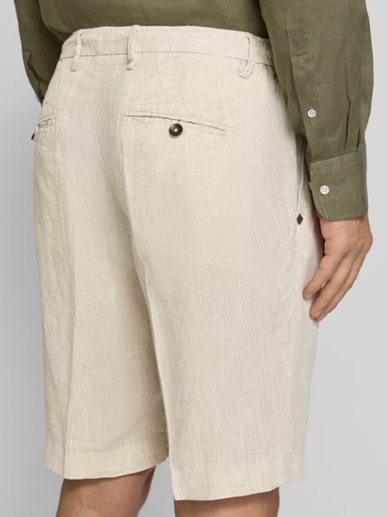 Männermodel trägt Shorts aus Leinen mit Eingrifftaschen von MARKUP in Beige, gerade Passform, sichtbare Gesäßleistentaschen, Ganzkörperansicht Rückansicht.