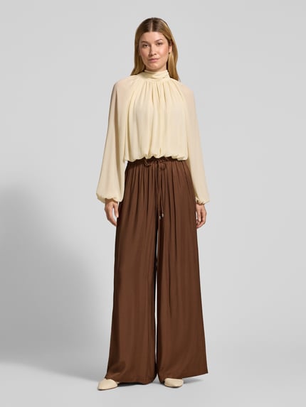 Frauenmodel trägt Weite Hose mit Tunnelzug von BOSS Orange, unifarben, elastischer Bund, gerippter Beinabschluss, Ganzkörperansicht von vorne.