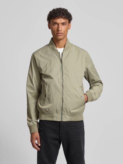 Männermodel trägt Regular Fit Bomberjacke mit Stehkragen van s.Oliver RED LABEL, unikleurig, rits, zijflapzakken, ribboorden, Ganzkörperansicht von vorne.