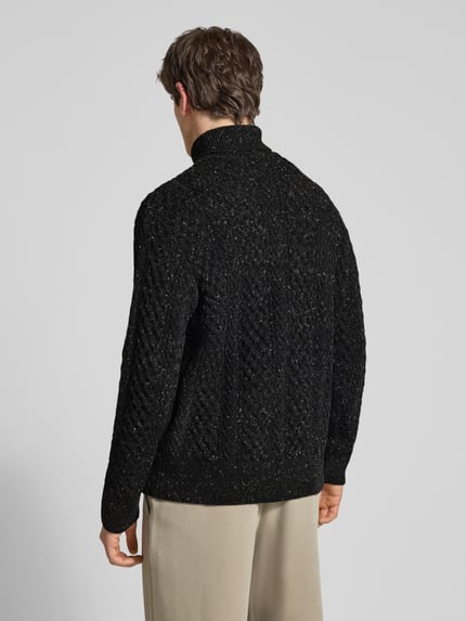 Männermodel trägt Rollkragenpullover mit Zopfmuster-Struktur von Selected Homme in schwarzer Strickoptik, Ganzkörperansicht Rückansicht.