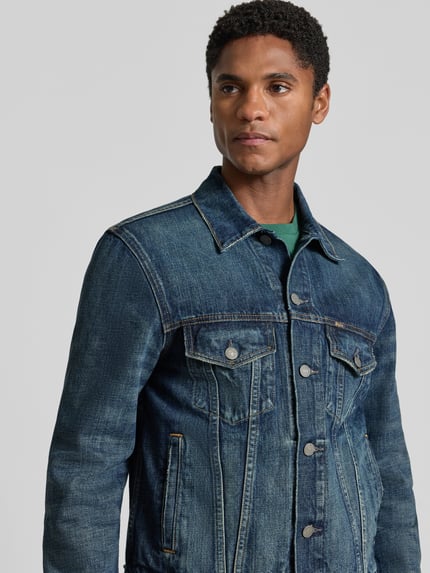Männermodel trägt Regular Fit Jeansjacke aus reiner Baumwolle Modell 'ICON' von Polo Ralph Lauren, mittleres Blau mit sichtbarer Struktur, Nahaufnahme Oberkörper.