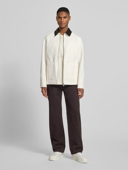 Männermodel trägt Regular Fit Jacke mit aufgesetzten Taschen Modell 'KALENO' von Drykorn, weiße Baumwolle, Umlegekragen, Ganzkörperansicht von vorne.
