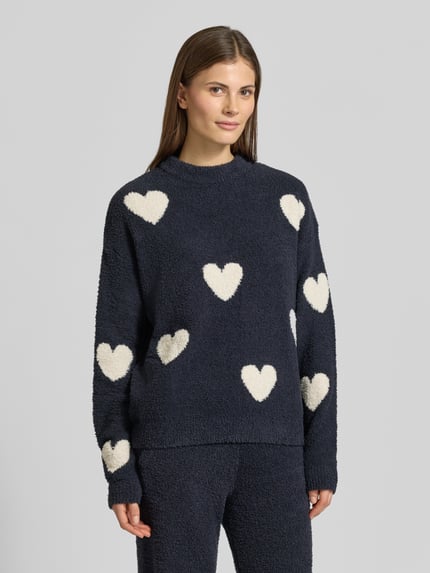 Frauenmodel trägt Strickpullover im Allover-Look von Jake*s Casual in Dunkelblau mit weißen Herzen, strukturierte, weiche Textur, Relaxed-Fit, Rundhalsausschnitt, überschnittene Schultern, Rückenlänge 56 cm, Ärmellänge 54 cm, Nahaufnahme Oberkörper.