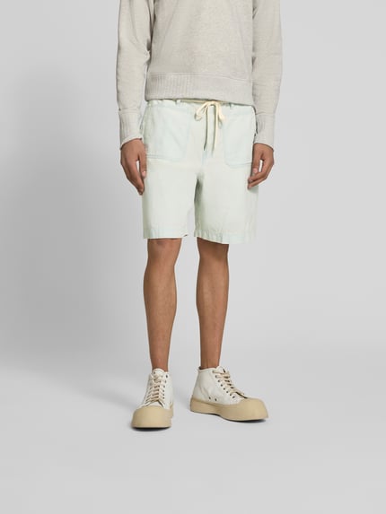 Mężczyzna nosi Shorts mit aufgesetzten Taschen von Kenzo z bawełny, krój relaxed fit, jasne kolory, kieszenie naszywane, widok z przodu, pełna sylwetka.
