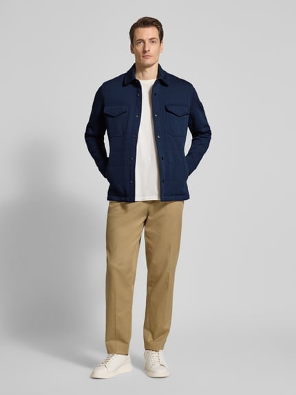 Männermodel trägt Regular Fit Sweatjacke aus Baumwoll-Mix von Tommy Hilfiger in Dunkelblau mit Druckknopfleiste, unifarben, Ganzkörperansicht von vorne.