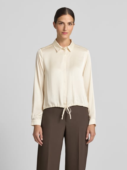 Kobieta modelka nosi Regular Fit Bluse aus Viskose mit verdeckter Knopfleiste von Milano Italy, kremowa bluzka z kołnierzykiem koszulowym, tunel, długi rękaw, długość tyłu w rozmiarze 36: 53 cm, długość rękawów w rozmiarze 36: 62 cm, brązowe spodnie, prosta gładka tkanina, widok całej sylwetki z przodu.