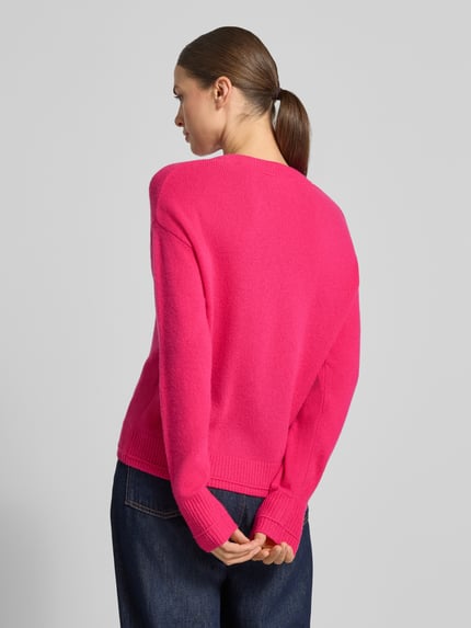 Modelka kobieca nosi różowy Strickpullover mit überschnittenen Schultern von Christian Berg Woman, luźny krój, prążkowane wykończenia, okrągły dekolt, długie rękawy, długość pleców w rozmiarze M: 60 cm, długość rękawa w rozmiarze M: 58 cm, widok całej sylwetki z tyłu.