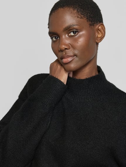 Frauenmodel trägt Turtleneck-Pullover mit Woll-Anteil und Rundhalsausschnitt von Neo Noir in Schwarz, gerippter Halsausschnitt, Nahaufnahme Oberkörper.