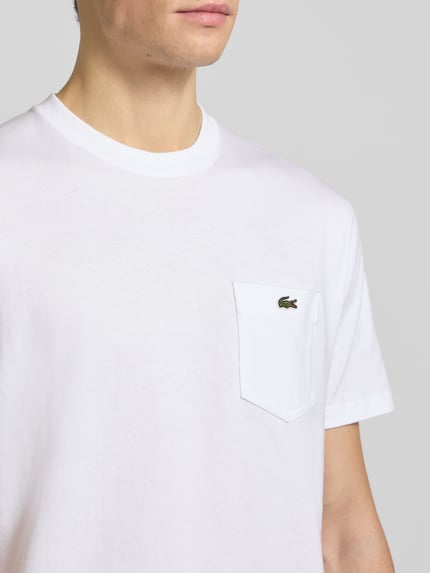 Männermodel draagt Regular Fit T-Shirt aus reiner Baumwolle van Lacoste, look: effen, regular fit pasvorm, gestikt logo, labelprint, ronde hals, puur katoen, Nahaufnahme Oberkörper.