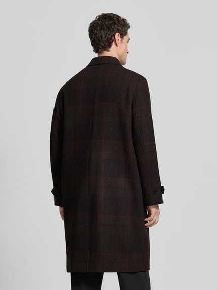 Männermodel trägt Mantel mit verdeckter Knopfleiste Modell 'Mettos2641' von HUGO, kariertes Allover-Muster, lange Ärmel, Gehschlitz, Ganzkörperansicht Rückansicht.