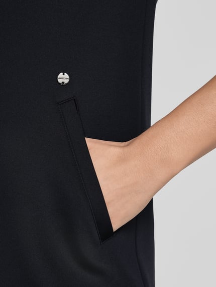 Vrouwenmodel draagt knielanges Kleid met zij-steekzakken van Marc Cain, zwarte materiaalmix met stretch, detailopname zak, dames jurk.