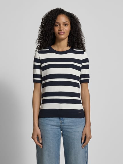 Frauenmodel trägt Strickshirt mit Rundhalsausschnitt und Label-Detail von More & More, gestreift in Blau und Weiß, Regular Fit, Viskose-Elasthan-Mix, Ganzkörperansicht von vorne.