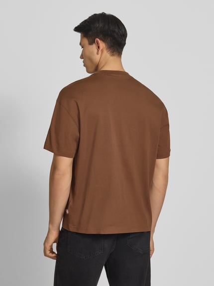 Męski model ma na sobie męski t-shirt z bawełny Dickies T-Shirt mit Label-Print Modell 'TORREY', krój regular fit, okrągły dekolt, długość tyłu w rozmiarze M: 70 cm, brąz, gładka tekstura, widok całej sylwetki z tyłu.