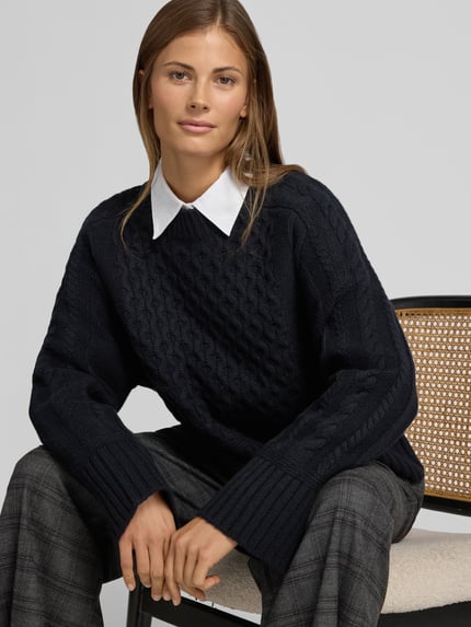 Frauenmodel trägt Strickpullover mit Zopfmuster von Style Icon Collection aus reiner Baumwolle, lockere Passform, Nahaufnahme Oberkörper.