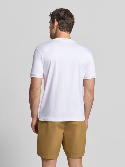 Męski model nosi białą koszulkę Slim Fit T-Shirt aus reiner Baumwolle Modell 'Tessler 195' von BOSS, brązowe szorty, gładka tekstura, Ganzkörperansicht Rückansicht