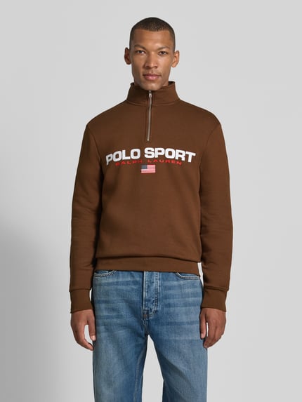 Männermodel trägt Relaxed Fit Troyer aus Baumwoll-Mix von Polo Ralph Lauren in Braun mit weiß-rotem Logo, Ganzkörperansicht von vorne. Herren Troyer von Polo Ralph Lauren