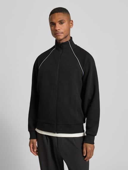Männermodel trägt Regular Fit Sweatjacke aus Baumwoll-Mix von BOSS Green, schwarz mit Kontraststreifen, Ganzkörperansicht von vorne.