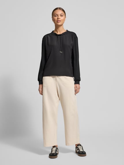 Frauenmodel trägt Longsleeve mit Rundhalsausschnitt von Marc Cain in Schwarz, lockerer Schnitt, Baumwoll-Elasthan-Mix, Ganzkörperansicht von vorne.