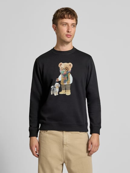 Mężczyzna nosi bluzę Sweatshirt mit Motiv-Print od CHILL PILL, mieszanka bawełny, krój regular fit, nadruk z motywem, okrągły dekolt, długość tyłu w rozmiarze M: 68 cm, długość rękawów w rozmiarze M: 74 cm, widok całej sylwetki z przodu.
