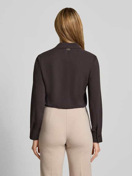 Vrouwenmodel draagt Blusenshirt met Umlegekragen van Rinascimento in recht fit, donkere kleur, lange mouwen met manchetten, rugaanzicht, ruglengte 47 cm, mouwlengte 59 cm.
