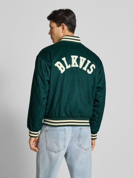 Männermodel trägt College Jacke mit Label-Patch von BLKVIS in Dunkelgrün, Material-Mix mit Woll-Anteil, Regular-Fit, Rückenansicht.