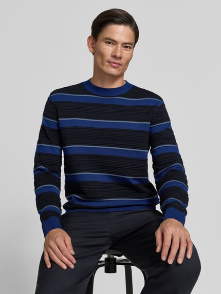 Männermodel trägt Strickpullover mit Struktur-Muster von Armani Exchange, reine Baumwolle, Blau-Schwarz, lockerer Schnitt, Nahaufnahme Oberkörper.