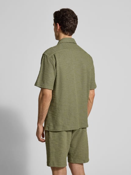 Männermodel trägt Regular Fit Freizeithemd mit Strukturmuster von MCNEAL in Olivgrün, Elastischer-Material-Mix, Kurzärmelig, Reverskragen, Ganzkörperansicht Rückansicht