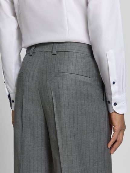 Männermodel trägt Regular Fit Bundfaltenhose aus Wolle von HUGO mit feinen Nadelstreifen, Webware, Bundfalte, Rückansicht, Detailaufnahme.