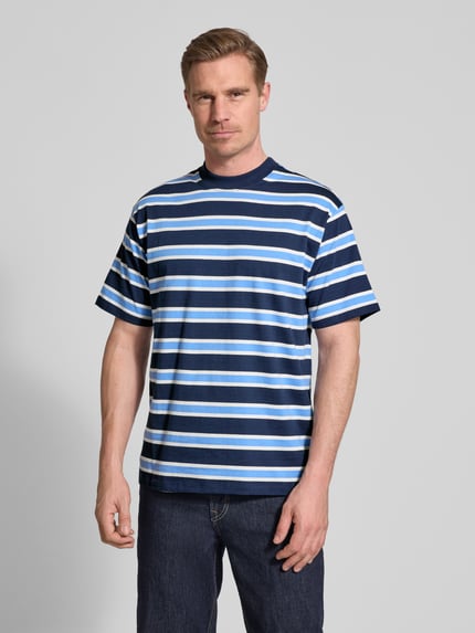 Männermodel trägt Regular Fit T-Shirt mit Rundhalsausschnitt von Casual Friday aus reine Baumwolle, blau gestreift, Kurzärmelig, Ganzkörperansicht von vorne.