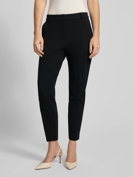 Frauenmodel trägt Stoffhose mit Gesäßtasche von Comma, schwarze Farbe, Viskose-Mix mit Stretch-Anteil, lockerer Schnitt, Bundfalten, französische Eingrifftaschen, Bundweite 38 cm, Innenbeinlänge 72 cm, Nahaufnahme Oberkörper.