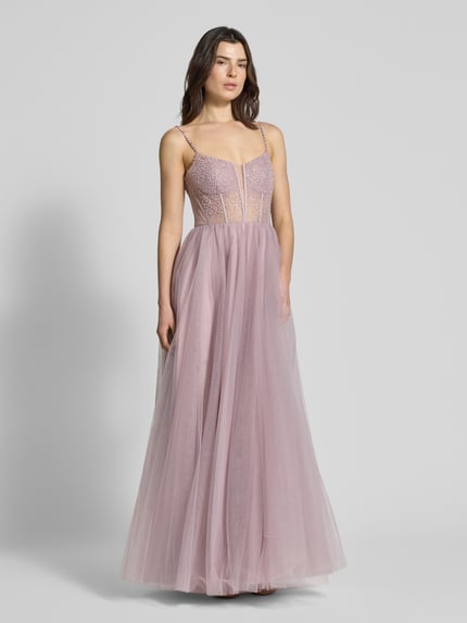 Frauenmodel trägt Regular Fit Abendkleid mit Ziersteinbesatz von Mascara, Mesh, taillierte Passform, Spaghetti-Träger, A-Linie, semitransparentes Design, Nahtreißverschluss, fließender Stoff, zarte Rosatöne, Ganzkörperansicht von vorne.