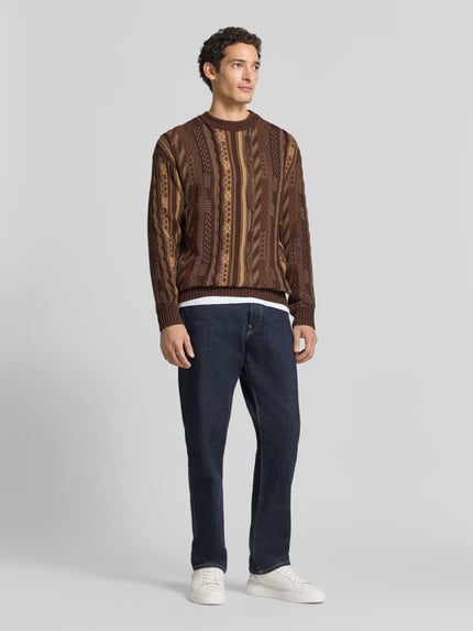 Männermodel trägt Regular Fit Strickpullover aus reiner Baumwolle von COLUCCI in Braun mit Muster, Kombination aus Stehkragen und gerippten Abschlüssen, Rückenlänge 73 cm, Ärmellänge 64 cm, Ganzkörperansicht von vorne.