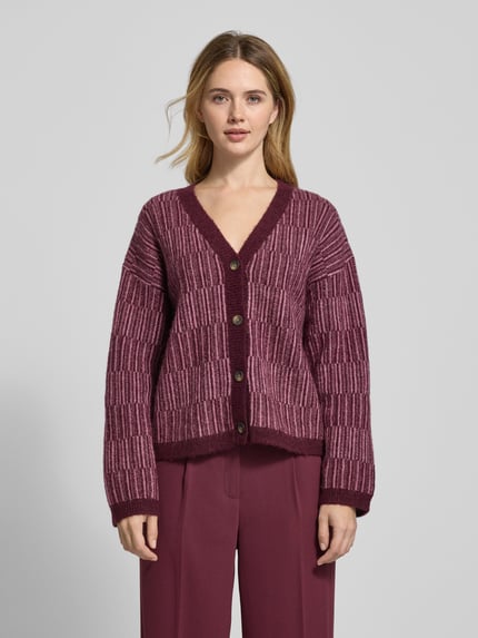 Frauenmodel trägt Relaxed Fit Strickpullover aus Woll-Mix mit Alpaka-Anteil Modell 'FALVA' von Selected Femme in Beerentönen, Strukturmuster, V-Ausschnitt, Knopfleiste, Ganzkörperansicht von vorne.