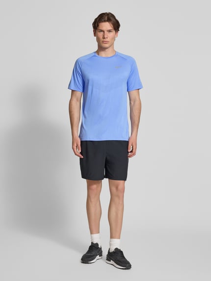 Männermodel trägt Funktionsshirt mit Logo und Rundhalsausschnitt Modell 'Stride' von NIKE TRAINING in Blau, Regular-Fit, Ganzkörperansicht von vorne. Rückenlänge bei Größe M: 73 cm.