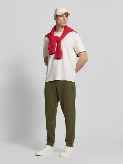 Męski model nosi Comfort Fit Sweatpants aus Baumwoll-Mix od Tommy Hilfiger, kolor jednolity, krój comfort fit, haftowane logo, troczek w pasie, ściągacze w pasie i u dołu, boczne kieszenie, materiał dresowy z mieszanki bawełny. Widok całej sylwetki z przodu.