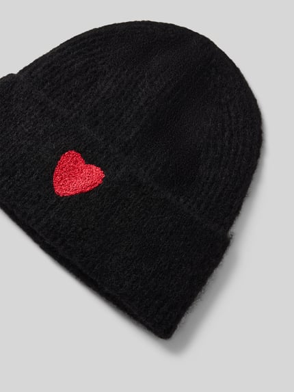 Produktfoto, schwarze Mütze mit Woll-Anteil von Jake*s Casual, rote Herzform als Akzent, strukturierte Oberfläche auf grauem Hintergrund.