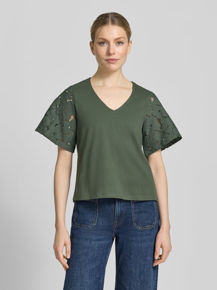 Frauenmodel trägt Regular Fit Blusenshirt aus reiner Baumwolle Modell 'VILLA' von Vero Moda, Optik: Unifarben, Spitzenbesatz, V-Ausschnitt, Ärmelform: Kurzarm, Materialverarbeitung: Jersey, Ganzkörperansicht von vorne.