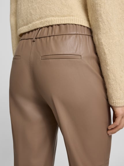 Vrouwenmodel draagt Loose Fit Pants in Leder-Optik model 'Luane' van OPUS PANTS, beige, glad oppervlak, detailopname achterkant.
