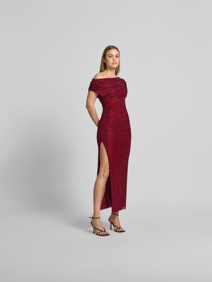 Kobiece modelka nosi długa sukienka 'Maxikleid mit Allover-Ziersteinbesatz' od Self-Portrait, elastyczna mieszanka materiałów, krój slim fit, obszycie z ozdobnym kamieni na całej powierzchni, marszczenia, krój z odkrytymi ramionami, całkowita długość w rozmiarze S: 130 cm, szerokość klatki piersiowej w rozmiarze S: 39 cm, szerokość w talii w rozmiarze S: 30 cm, widok całej sylwetki z przodu.